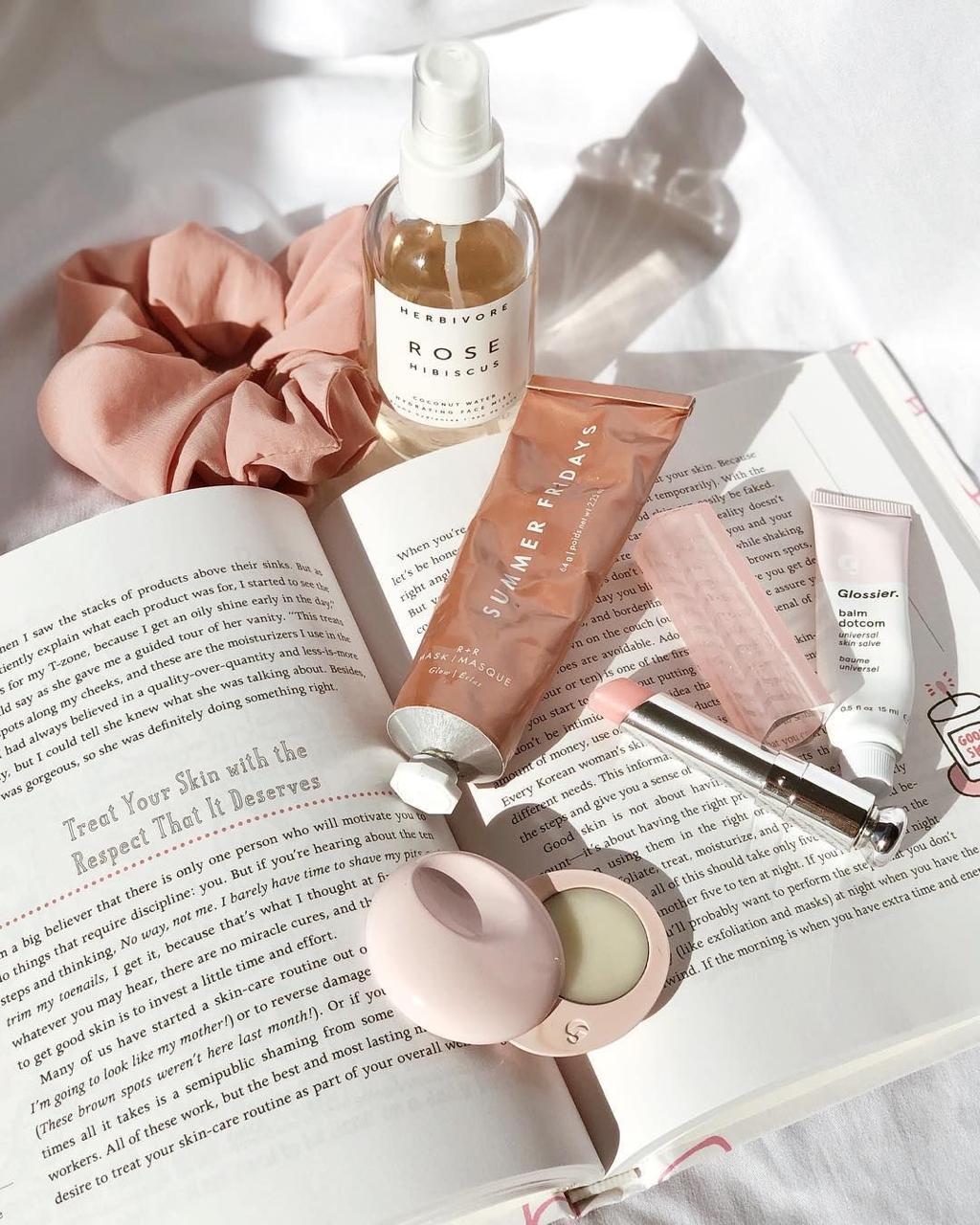 Treat yourself this Anti-Valentine’s Day with beauty self-care essentials under ₹4,999, including a Summer Fridays mask and Glossier balm, displayed across an open book in bright sunlight.