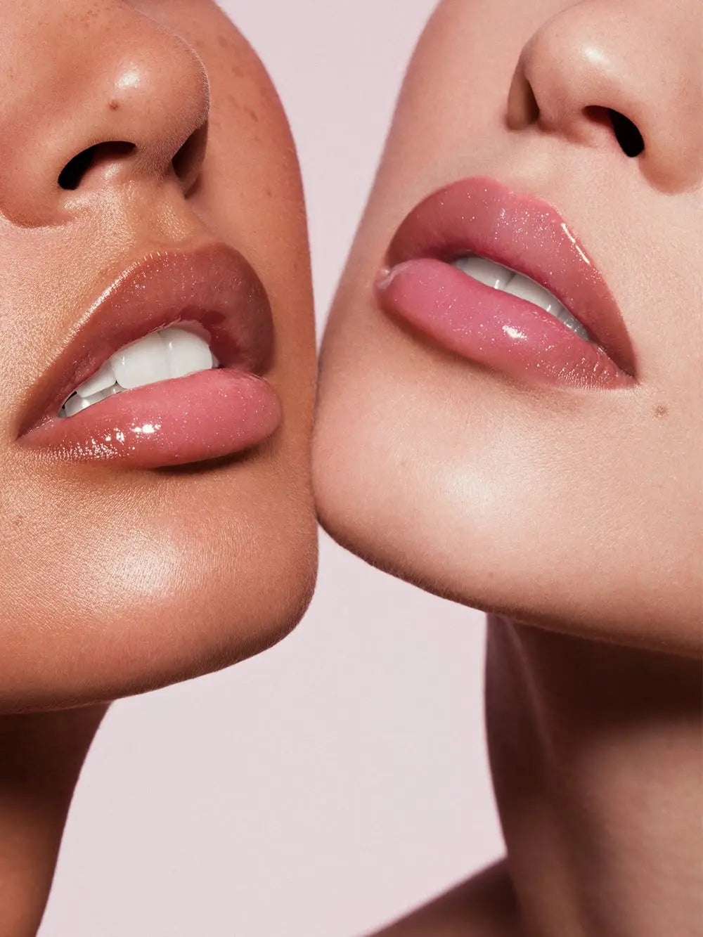 A model with straight blonde hair holding a Summer Fridays lip gloss tube that matches her glossy, rosy lips perfectly.