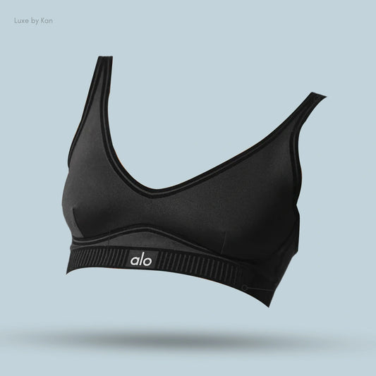 Alo Airlift Line Up Bra in black, flat lay on light blue background