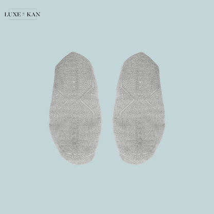 A pair of soft, light grey socks laid flat on a soft blue background, featuring textured patterns for style and comfort.