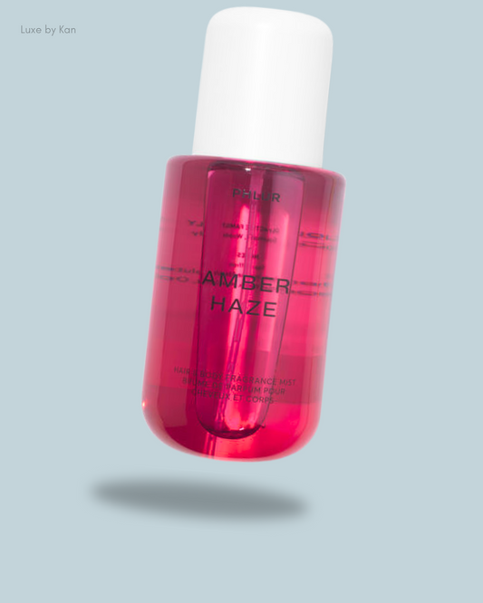 A pink bottle labeled "Amber Haze" with a white cap, featuring a sleek design against a soft gray background.