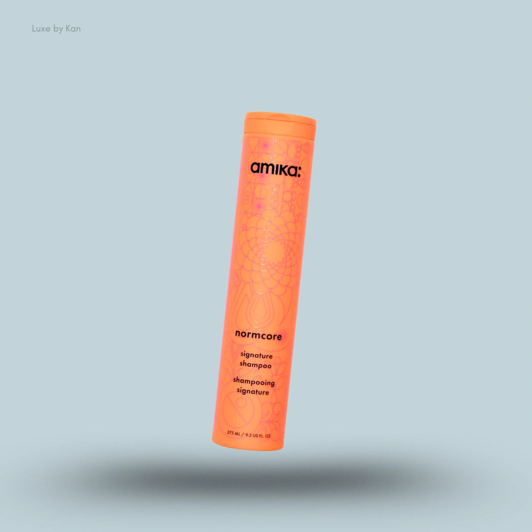 Amika Normcore Signature Shampoo bottle on blue background — Luxe by Kan India