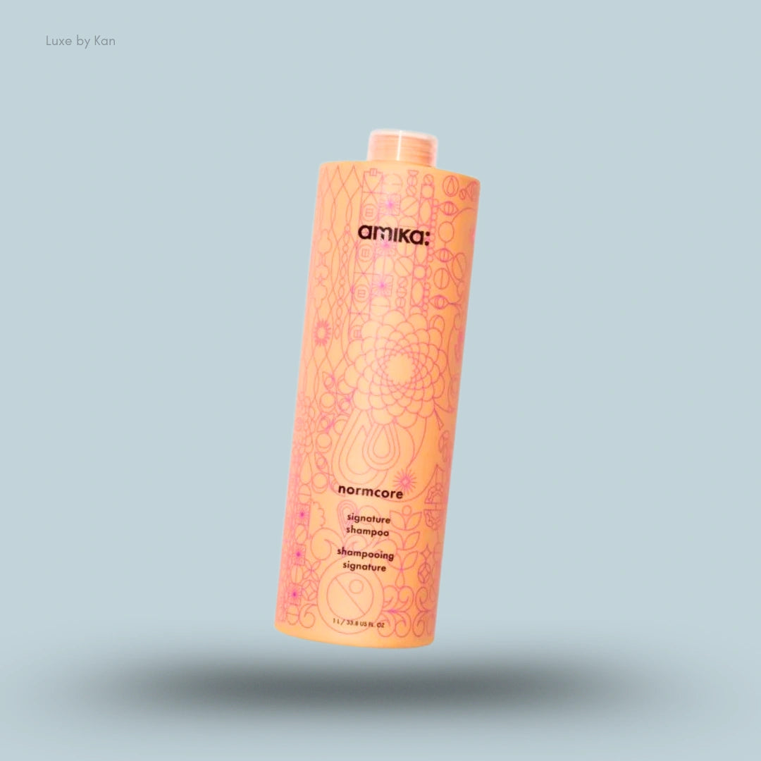 Amika Normcore Signature Shampoo bottle on blue background — Luxe by Kan India