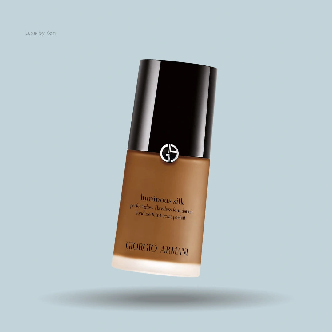Giorgio Armani Luminous Silk foundation bottle, tan color, black cap, against a light blue background.