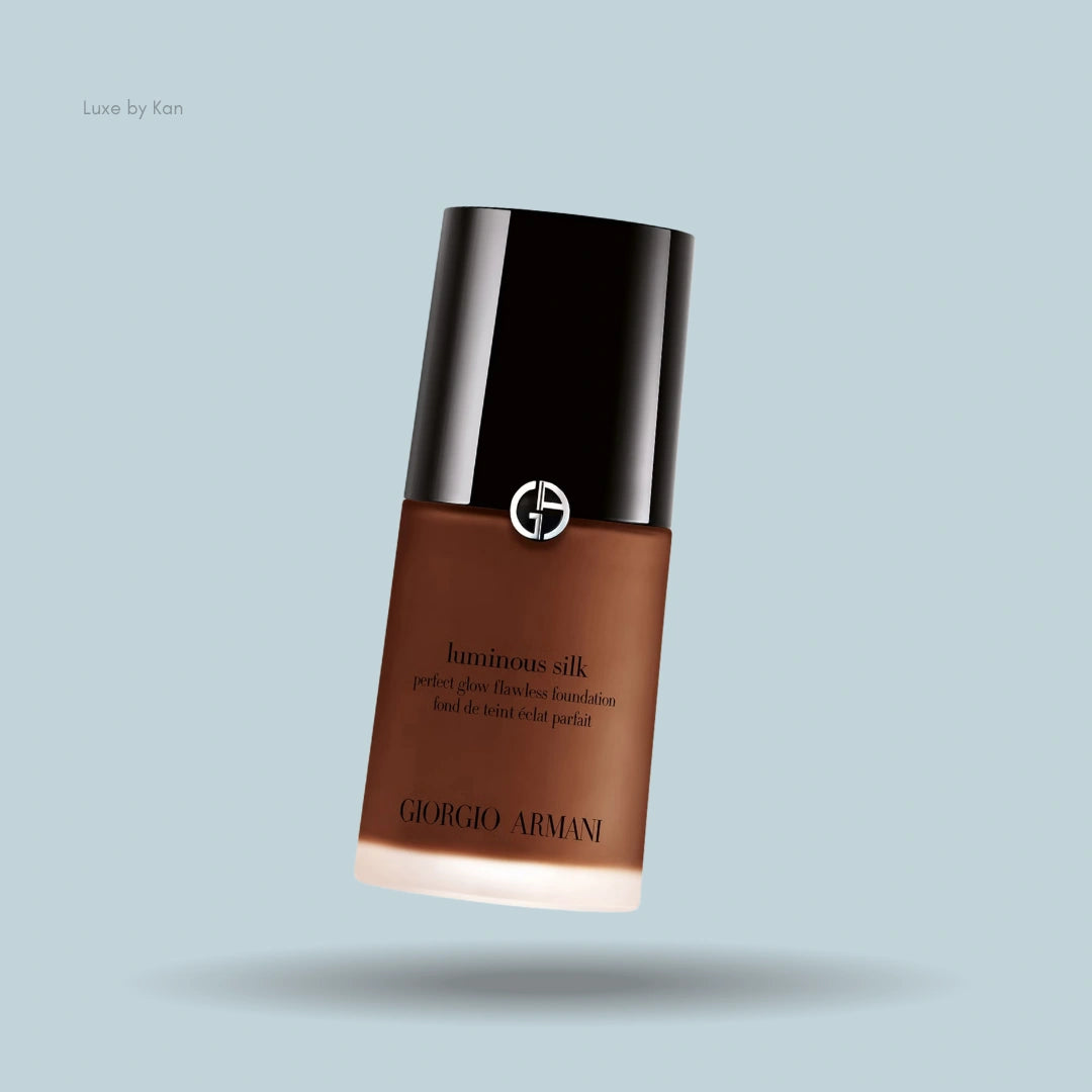 A bottle of Giorgio Armani Luminous Silk foundation, showcasing a sleek design with a black lid and golden logo.
