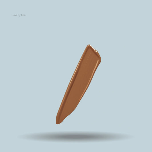  A swatch of Armani Power Fabric concealer in a caramel shade, isolated on a light blue background with a subtle drop shadow.