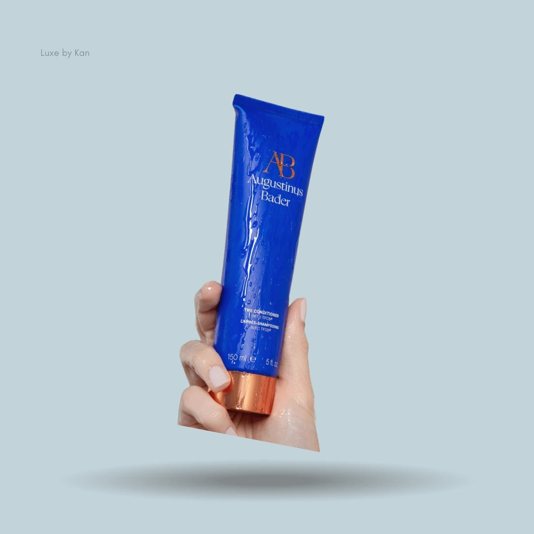 Hand holding Augustinus Bader "The Conditioner" tube.