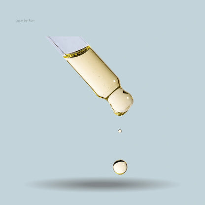 Augustinus Bader Hair Oil dropper releasing golden oil droplets.