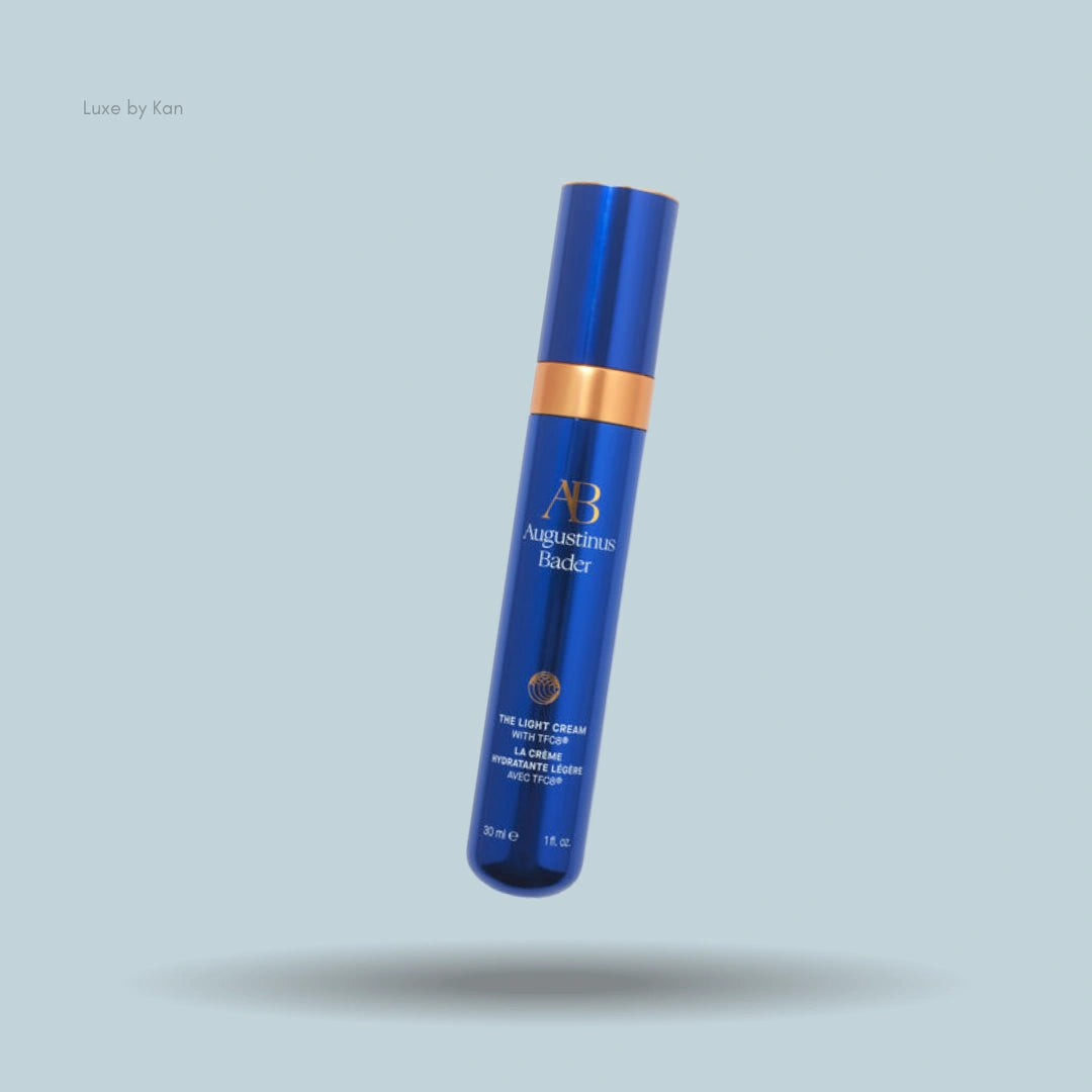 Augustinus Bader The Light Cream in a reflective blue bottle with a gold band.