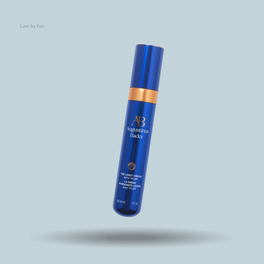 Augustinus Bader The Light Cream in a reflective blue bottle with a gold band.