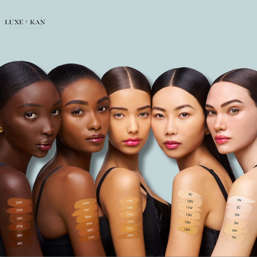 A lineup of diverse skin tones showcases foundation swatches on arms, labeled with various shades for skin tone matching.