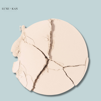 Close-up of cracked Chantecaille HD Perfecting Powder on a pale blue background.