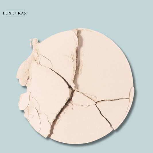 Close-up of cracked Chantecaille HD Perfecting Powder on a pale blue background.