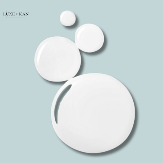 Four glossy white droplets representing Color Wow Money Mist, reflecting a minimalist and modern design aesthetic.