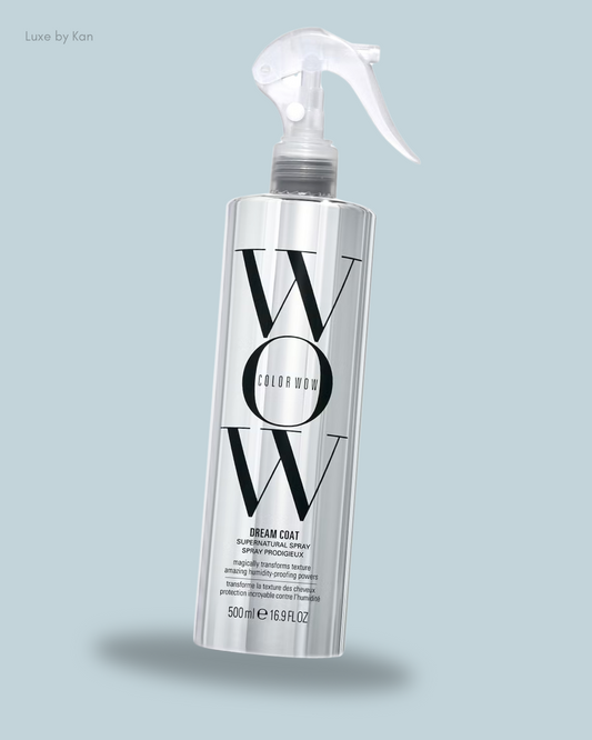 A sleek, silver spray bottle labeled "COLOR WOW Dream Coat Anti-Frizz Treatment" for hair, featuring humidity protection and transformative properties.