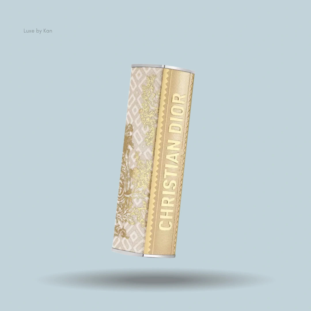 Dior Addict lipstick case featuring intricate gold floral patterns on a cream backdrop, with the "CHRISTIAN DIOR" logo embossed on a gold-textured surface.
