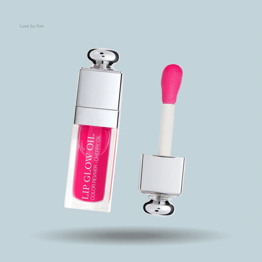 Dior Addict Lip Glow Oil in a vibrant cherry shade, showcased in a clear bottle with the applicator displayed on the right.