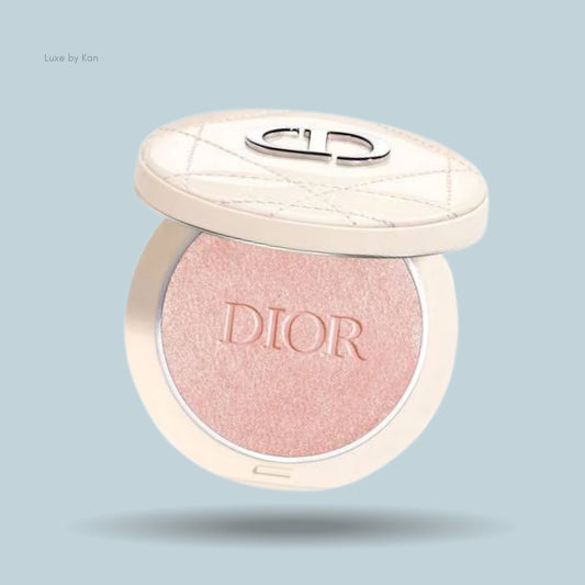 Close-up of an open Dior Forever Couture Luminizer compact. The powder inside is a pale pink shade with "DIOR" embossed on the surface.