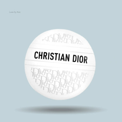A white, spherical Dior balm container with "CHRISTIAN DIOR" printed horizontally across the center.