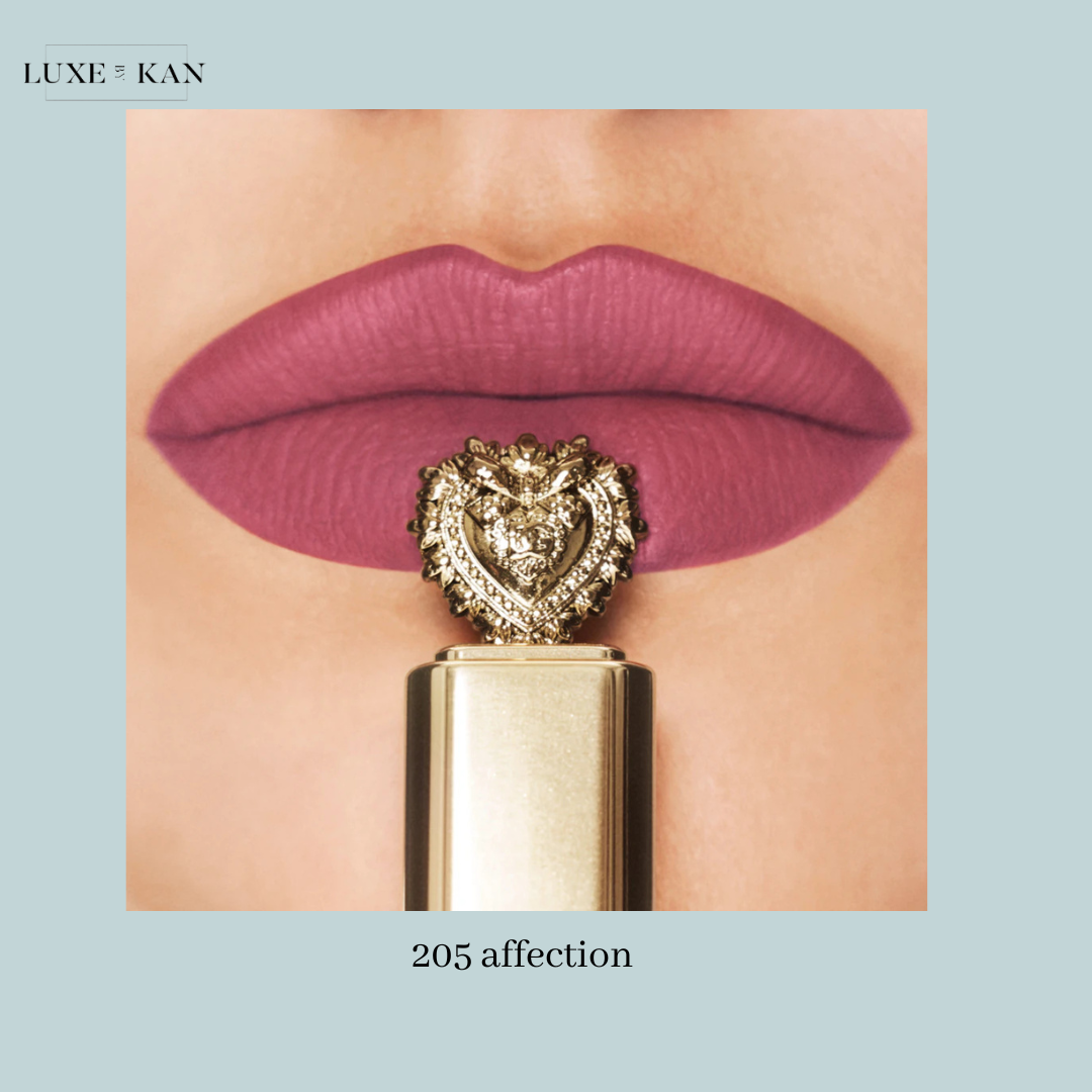 Close-up of bold mauve lips with a decorative gold and diamond lipstick cap, labeled "205 Affection." Elegant and striking.