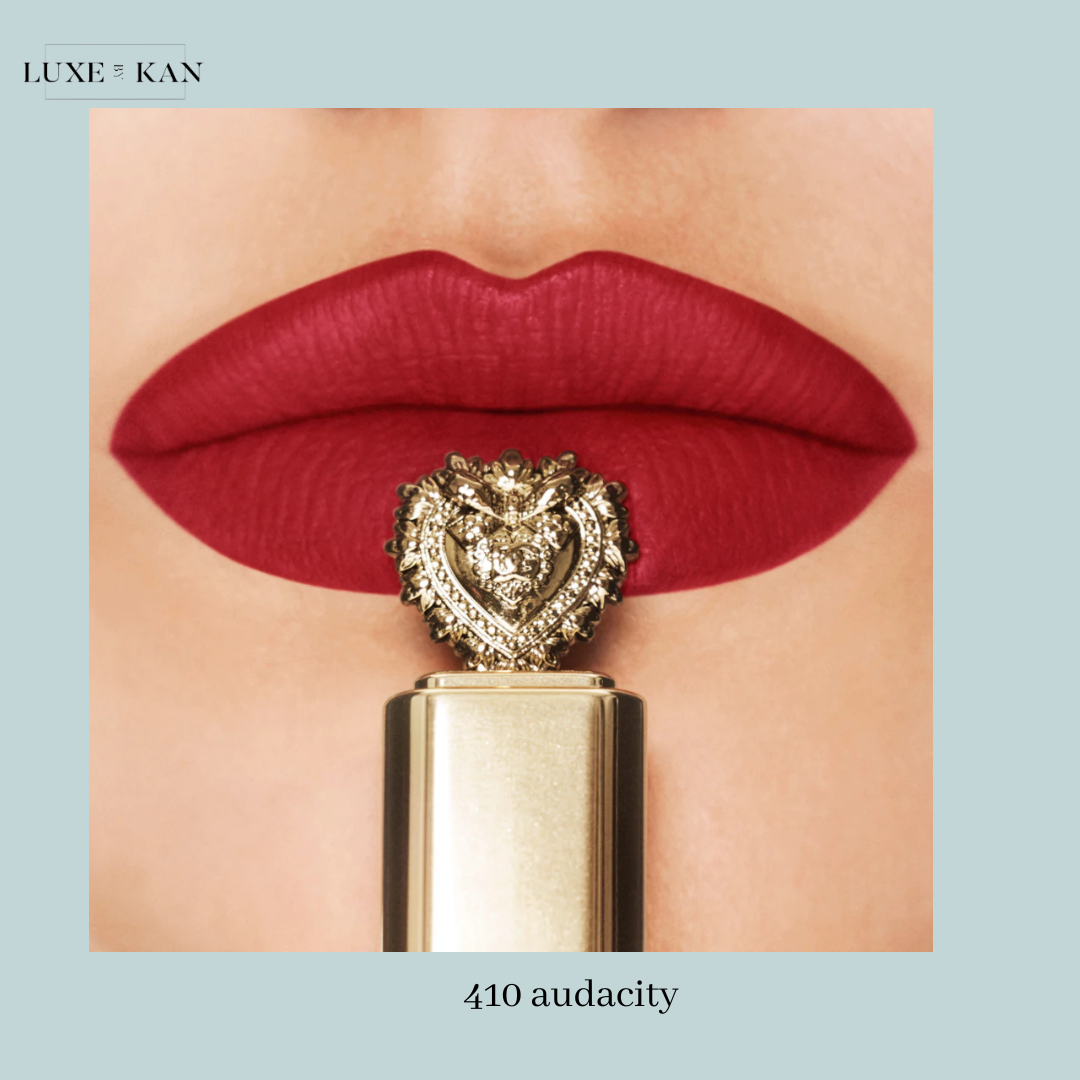 Close-up of bold red lips with a luxurious lipstick adorned with a gold lion emblem, labeled "410 audacity".