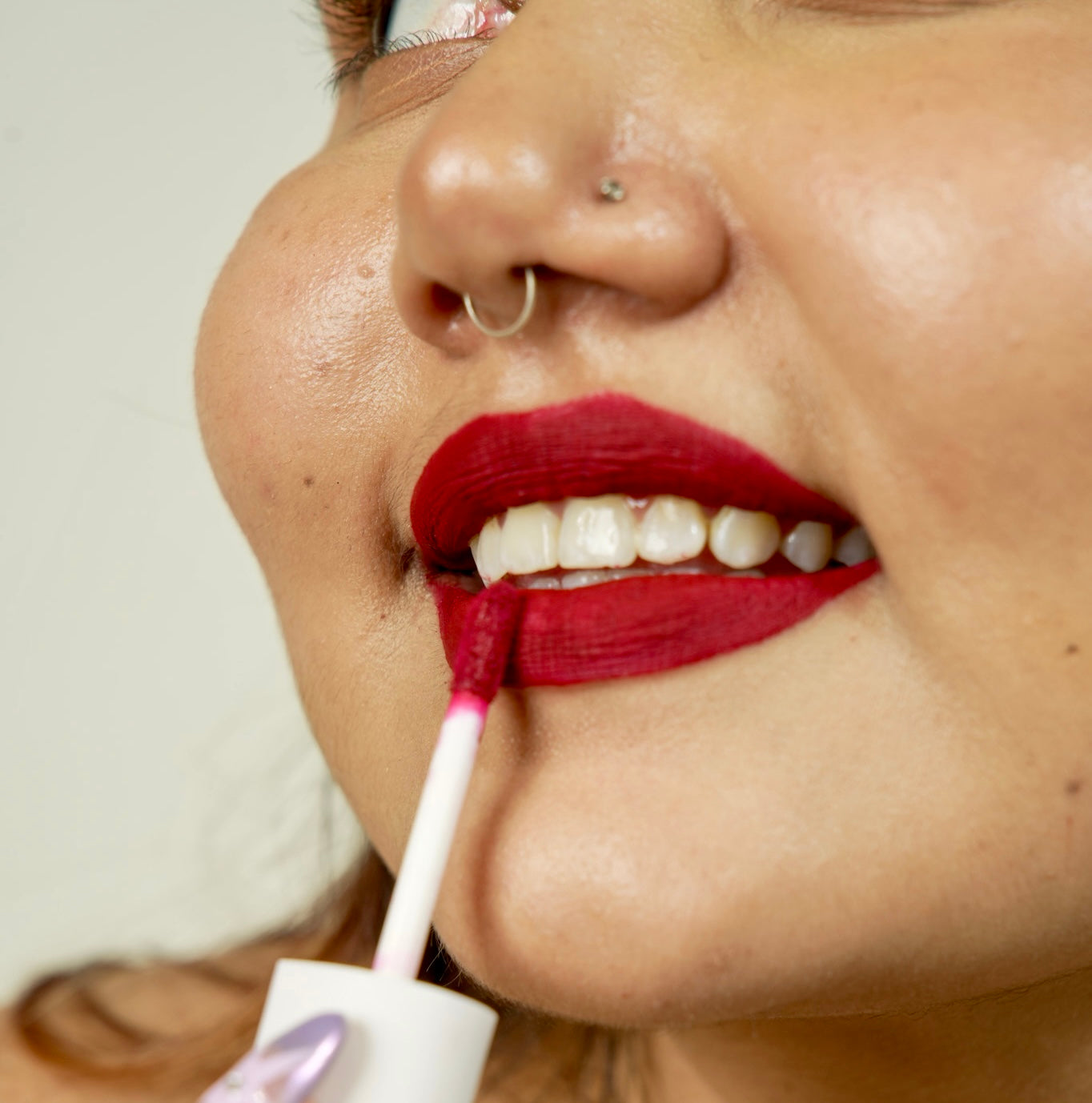 A woman is applying era beauty velvet liquid matte simp shade lipstick.