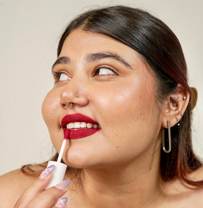 A woman is applying era beauty velvet liquid matte simp shade lipstick.