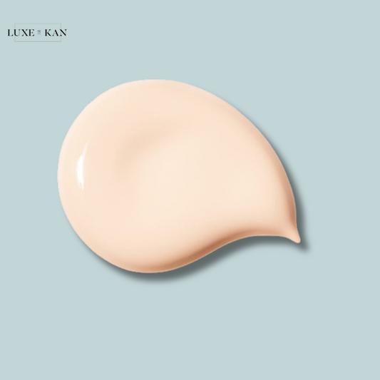 A creamy pale beige cosmetic swatch on a light blue background, showcasing a smooth texture.