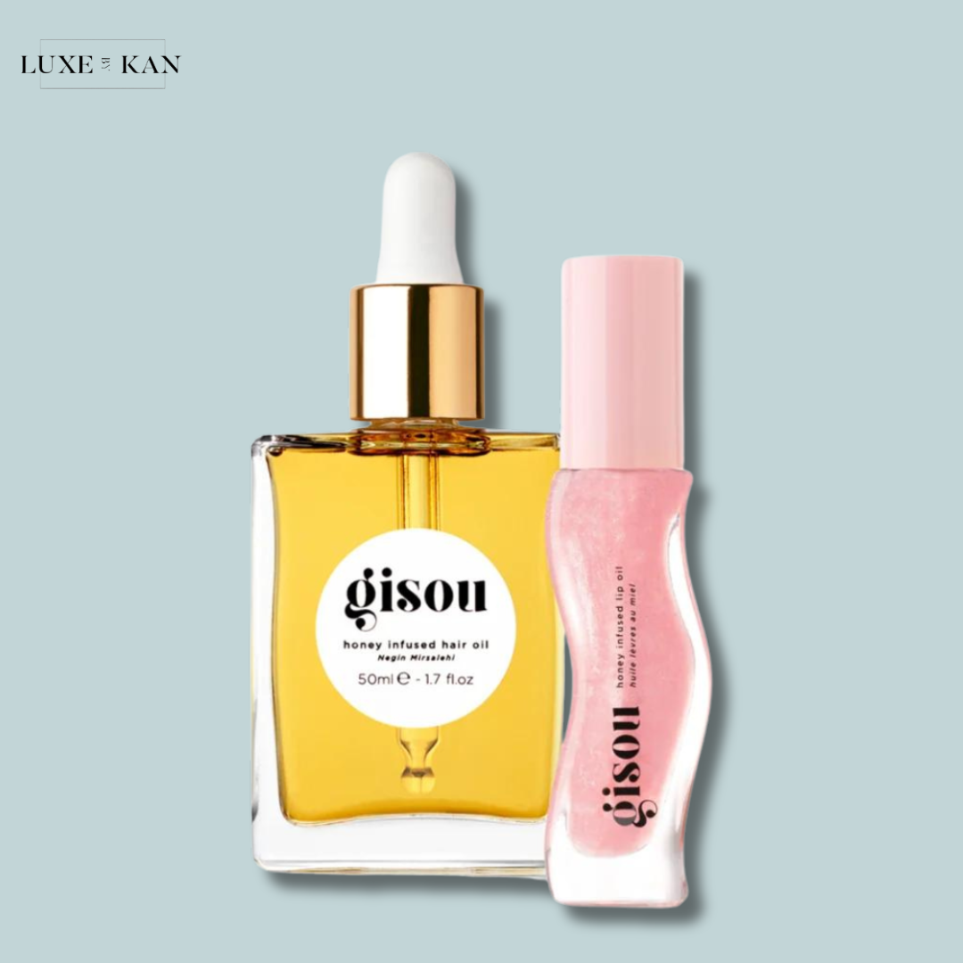 Gisou honey-infused hair oil in a glass bottle next to a pink lip oil.