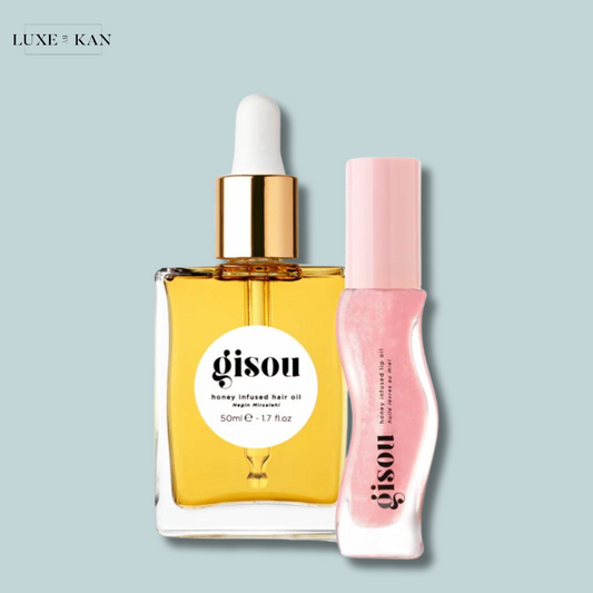 Gisou honey-infused hair oil in a glass bottle next to a pink lip oil.