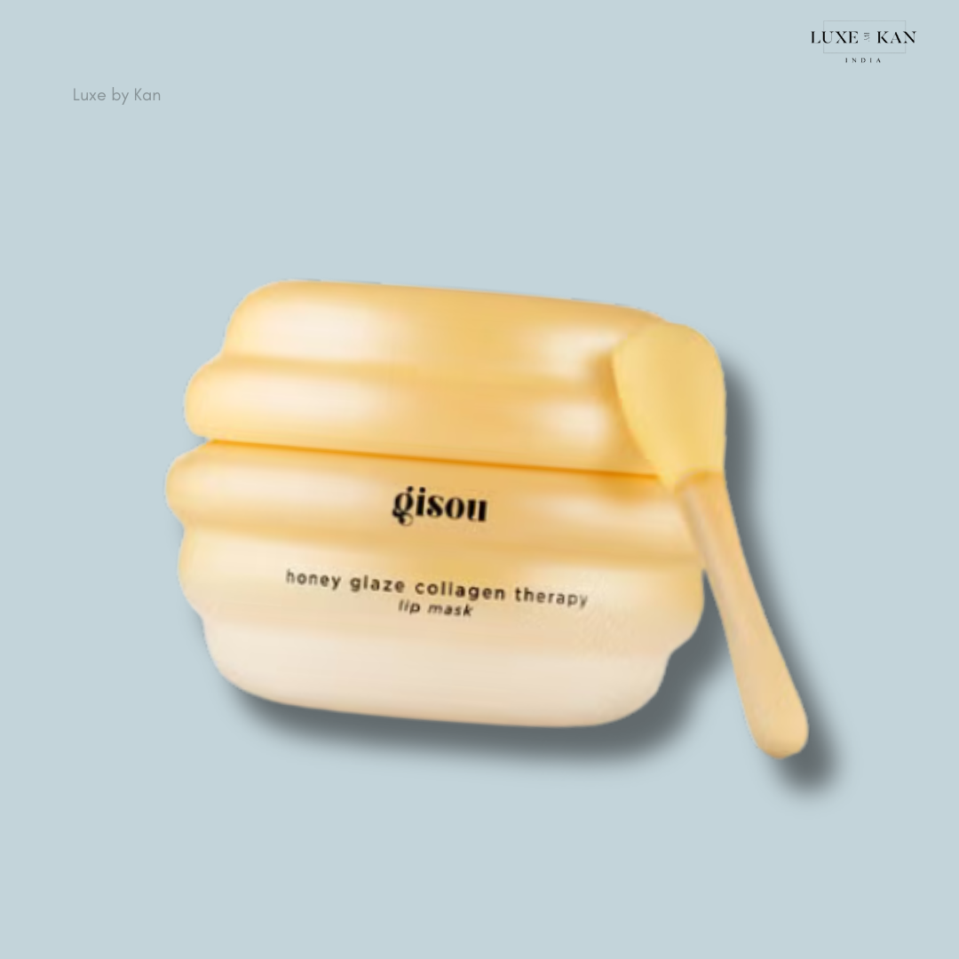 Gisou Honey Glaze Collagen Therapy Lip Mask in a yellow beehive-shaped jar with a small applicator on a blue background.