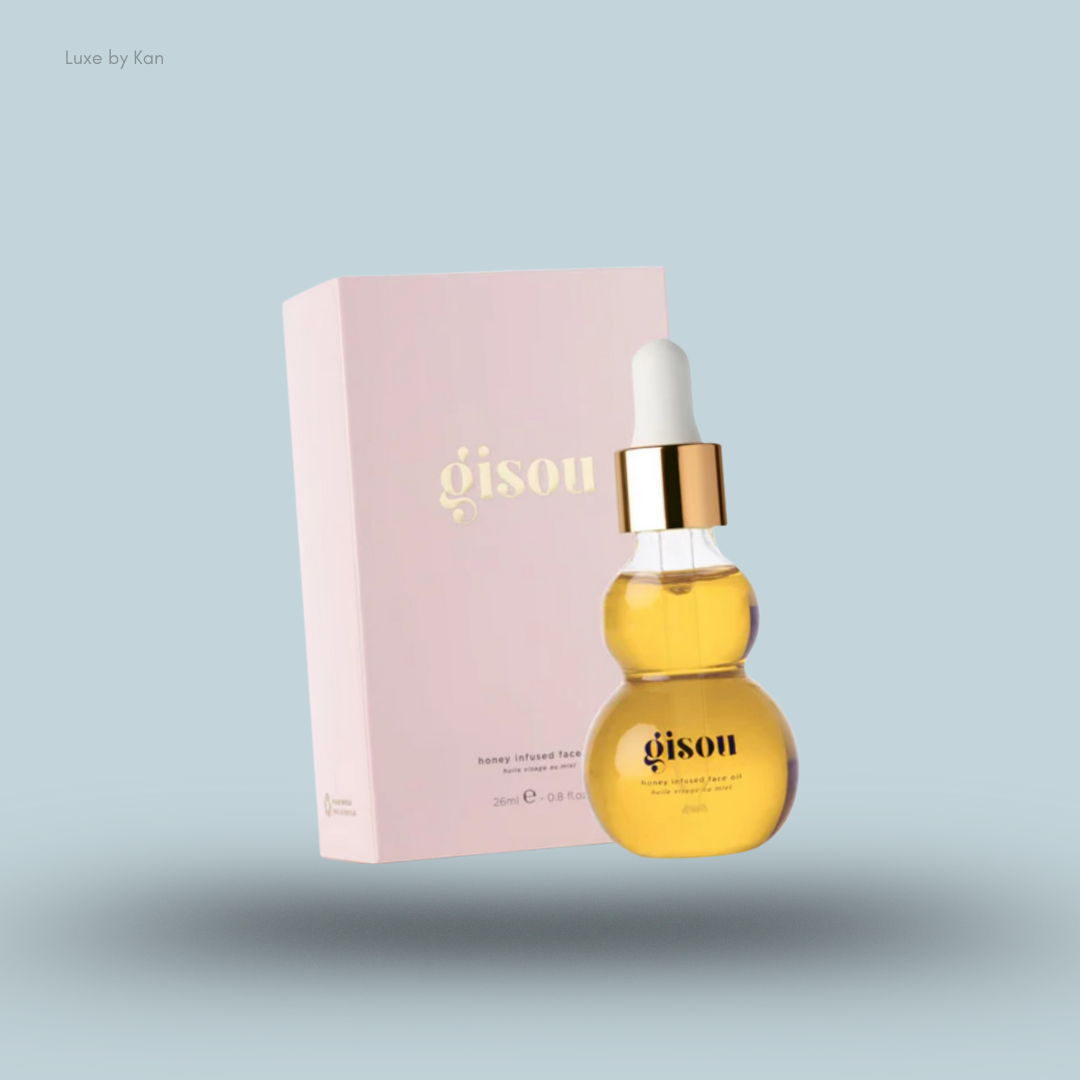 Gisou honey infused face oil in a curved glass dropper bottle next to its light pink box on a soft blue background.