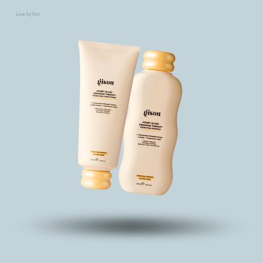 Two Gisou Honey Gloss hair products, a shampoo and conditioner, highlighting their elegant packaging.