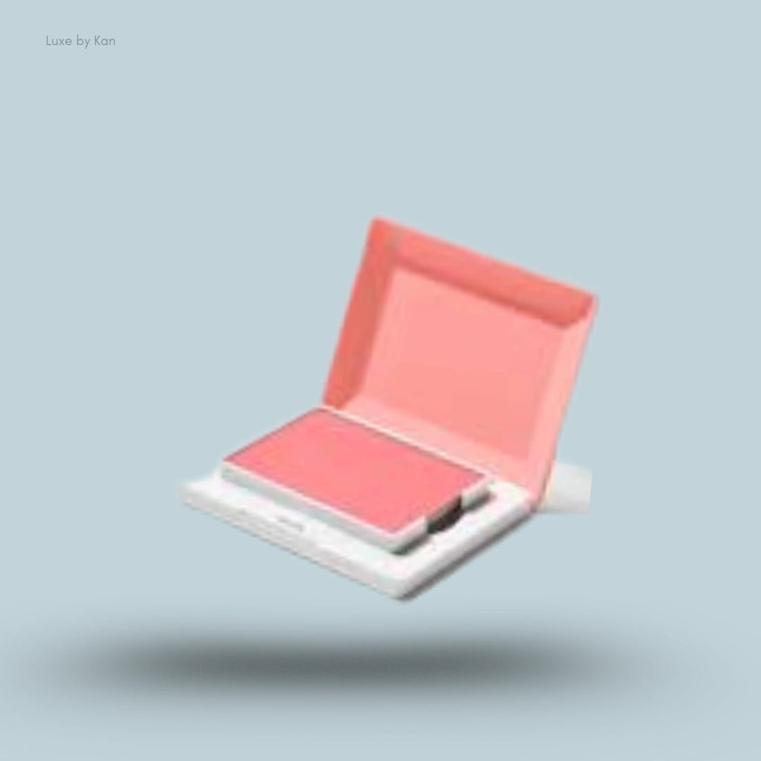 An open compact case with Glossier Cloud Paint Plush Blush in a bright coral pink shade floating against a light blue background.