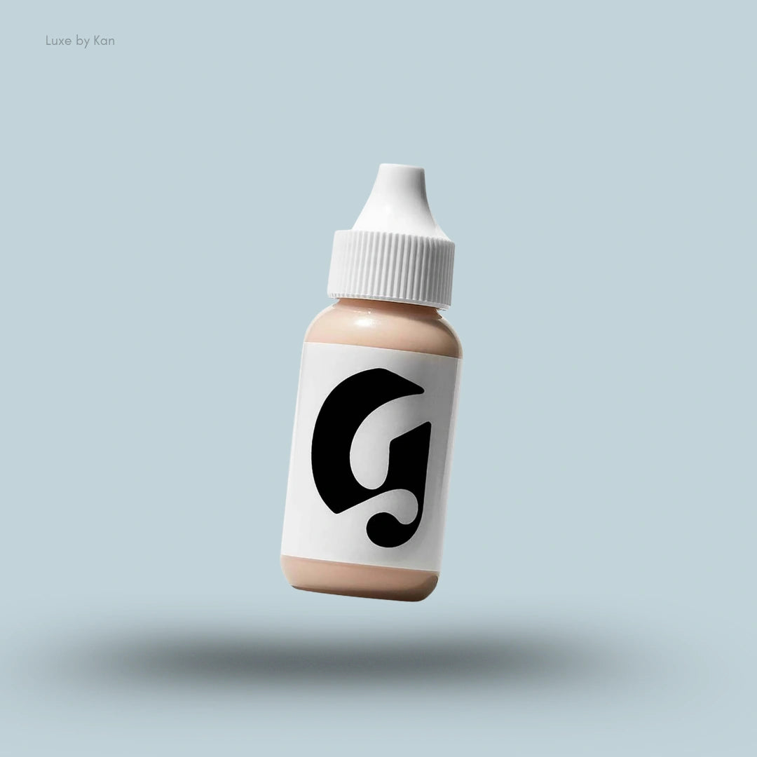Glossier Perfecting Skin Tint Sheer Skin Enhancer in a small dropper bottle with a white cap, floating on a light blue background.