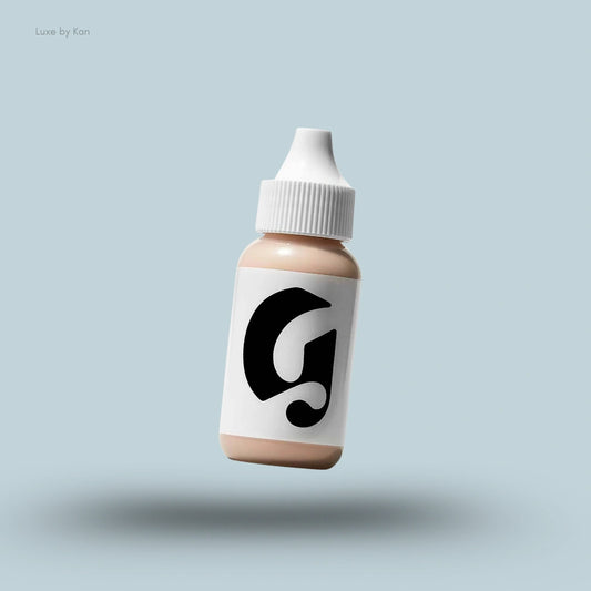 Glossier Perfecting Skin Tint Sheer Skin Enhancer in a small dropper bottle with a white cap, floating on a light blue background.