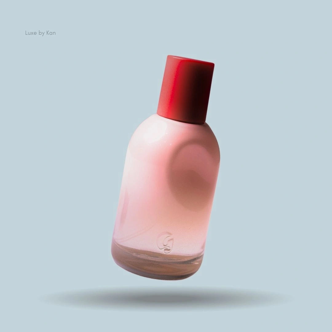 A pink bottle of Glossier You Eau De Parfum with a red cap floating gently against a light blue background.