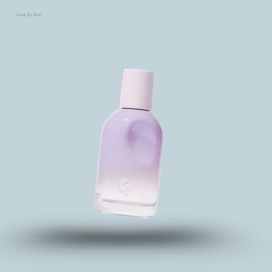 A pastel lavender and white Glossier You Fleur Perfume bottle with a light pink cap, floating on a pale blue background.
