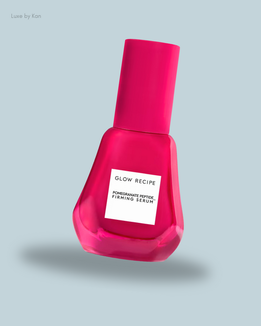 Bright pink bottle of Glow Recipe Pomegranate Peptide Firming Serum with a sleek, modern design against a soft blue background.