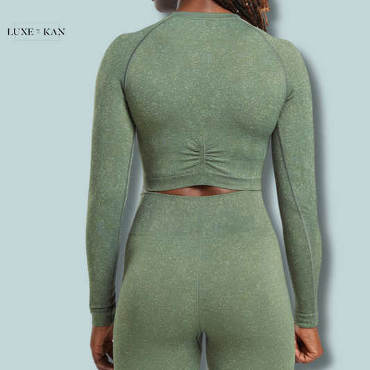 A woman wearing a green Adapt Fleck Seamless Long Sleeve Crop Top paired with matching leggings.