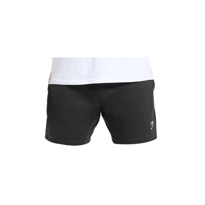 Close-up of Gymshark men's crest shorts in black with a white logo on the right leg and a white t-shirt above the shorts.