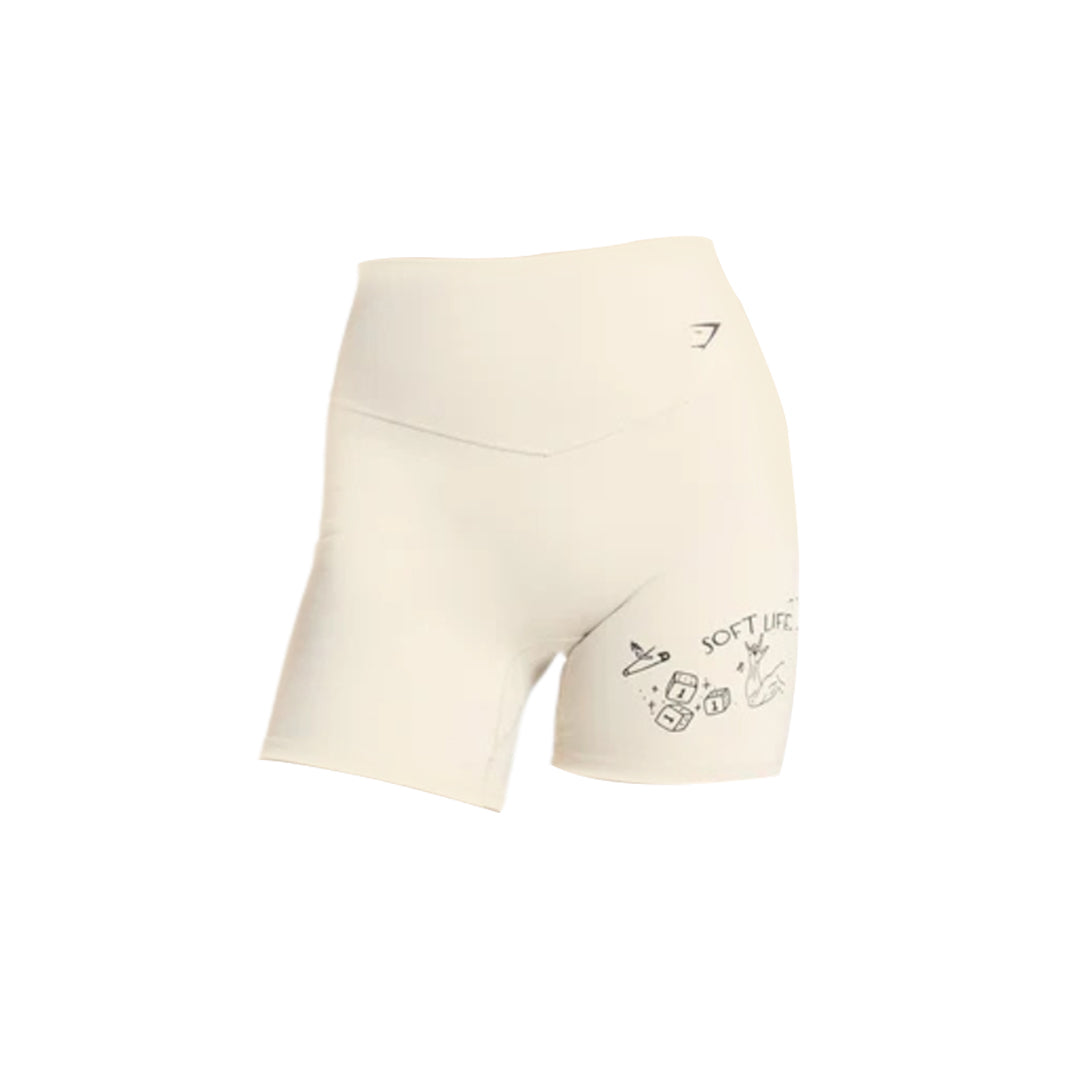 Cream-colored Gymshark athletic shorts featuring fun, playful graphics on the left leg, ideal for workouts and casual wear.