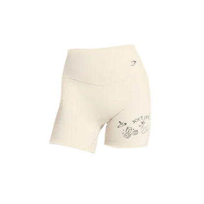 Cream-colored Gymshark athletic shorts featuring fun, playful graphics on the left leg, ideal for workouts and casual wear.