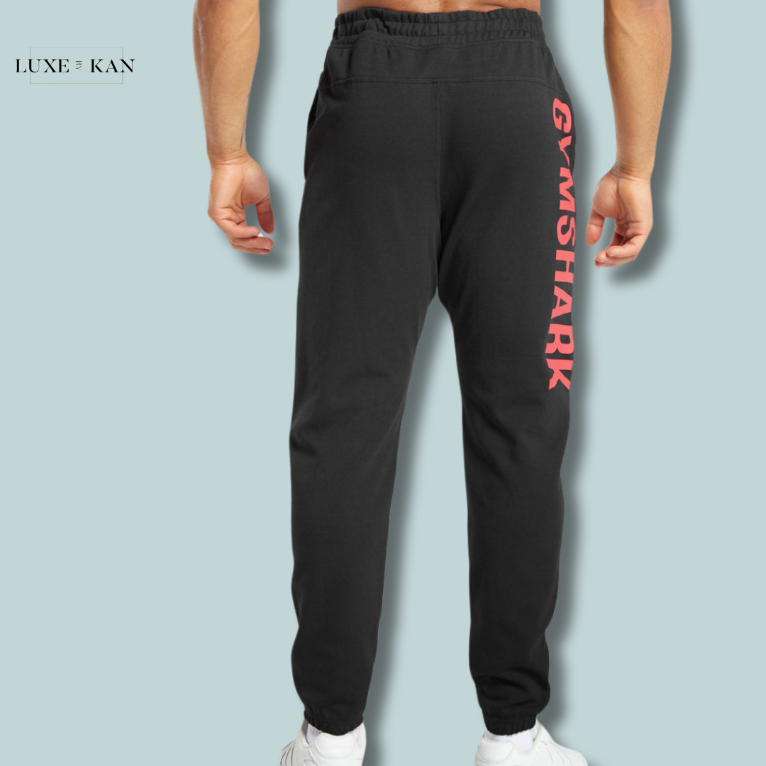 A man wearing black joggers with "GYMSHARK" printed in bold red on the side.