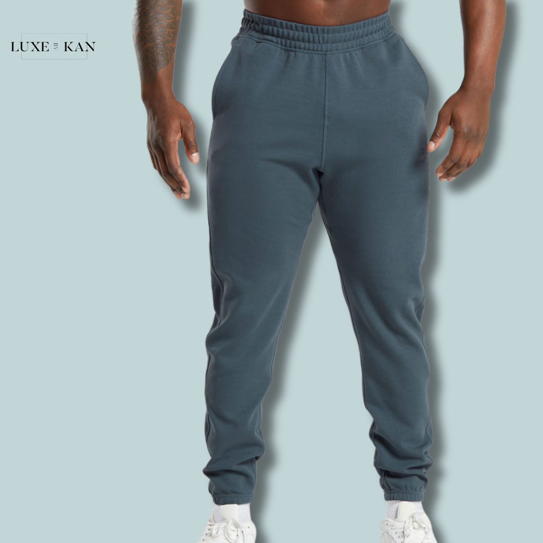 A muscular man wearing dark blue gymshark jogger and white sneakers.