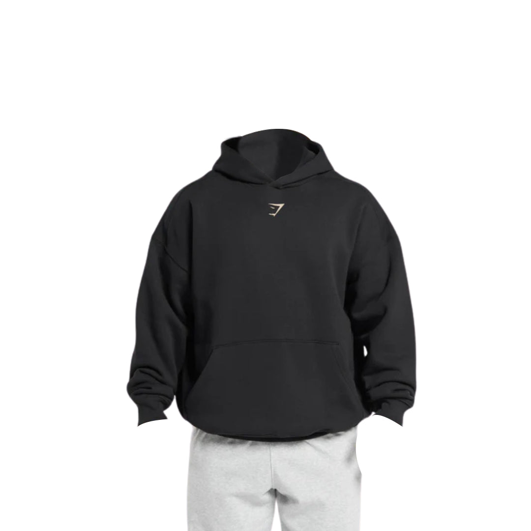 A black Gymshark Oversized Lifting Club Hoodie with a small chest logo, paired with light gray sweatpants on a mannequin.