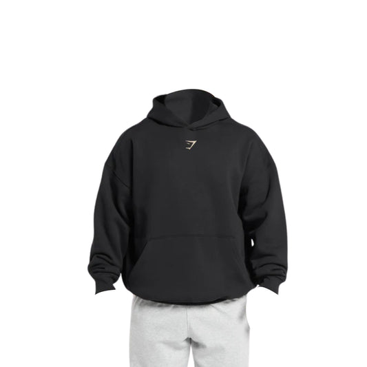 A black Gymshark Oversized Lifting Club Hoodie with a small chest logo, paired with light gray sweatpants on a mannequin.