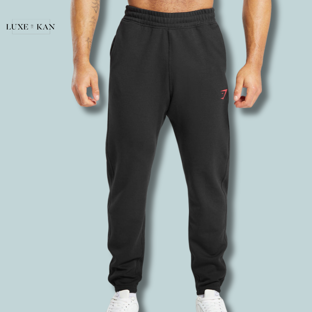 A muscular man wearing black gymshark impact joggers.