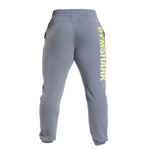 Gray sweatpants with a tapered fit and bright yellow "GYMSHARK" logo printed vertically on the left side, featuring side pockets.