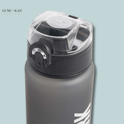 Gray gymshark water bottle with clear flip-top lid against a light blue background.